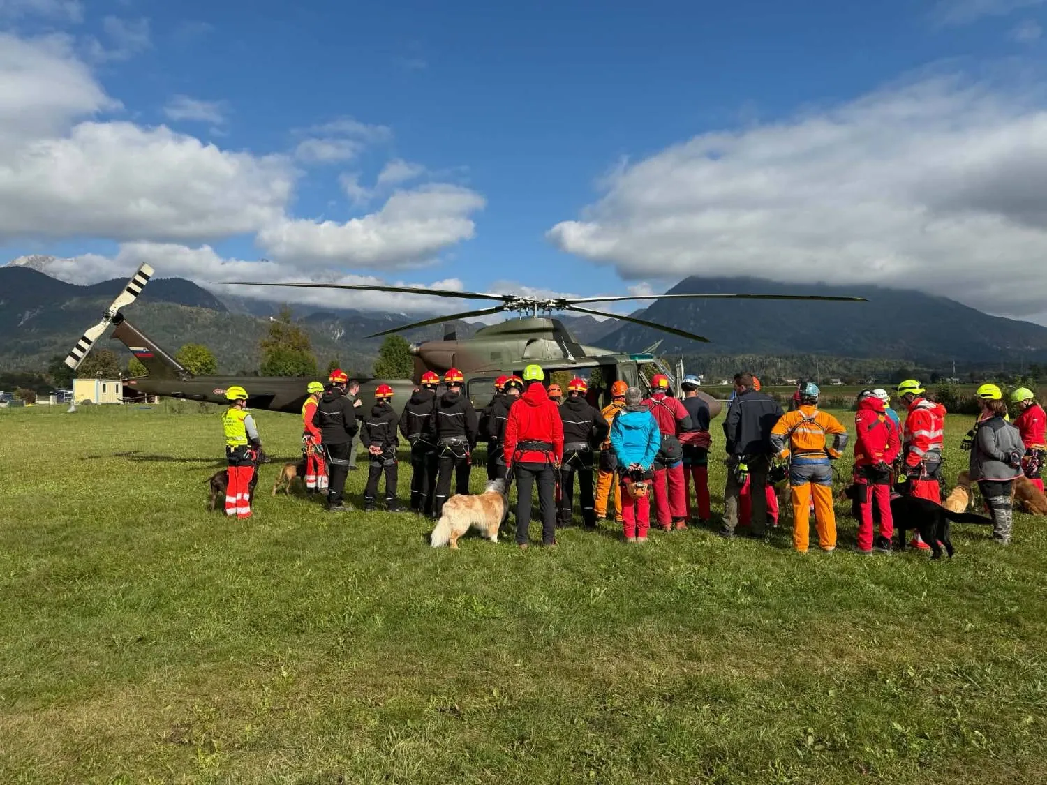 Vodniki s psi in drugi reševalci med navodili pred helikopterjem.