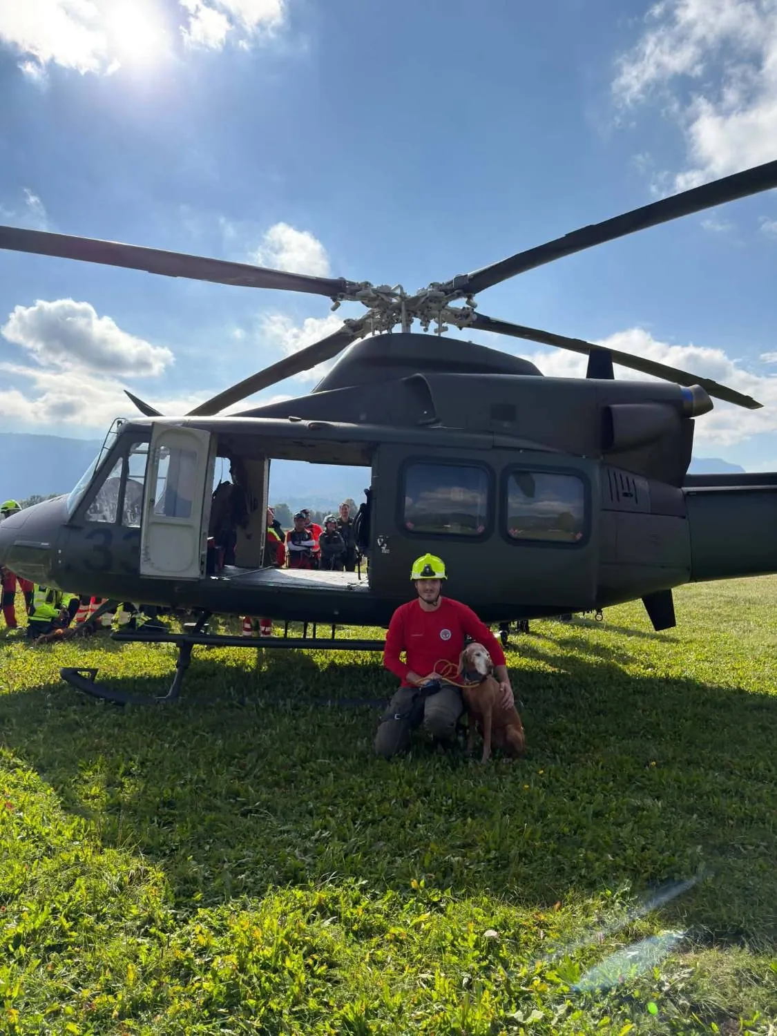 Vodnik v čeladi s psom pred odprtim helikopterjem.